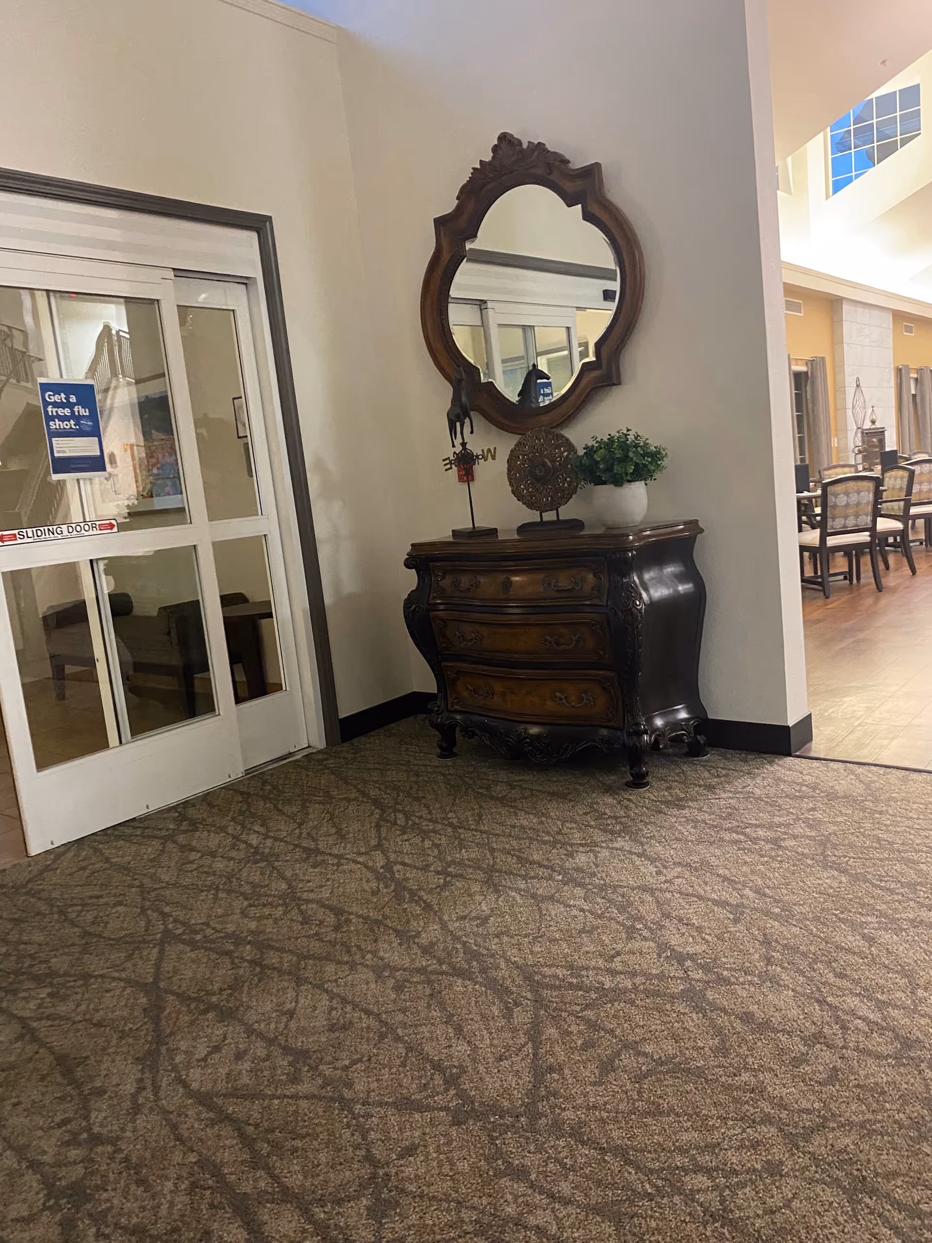 Ornate vintage dresser with carved mirror in a lobby area of a senior living facility.