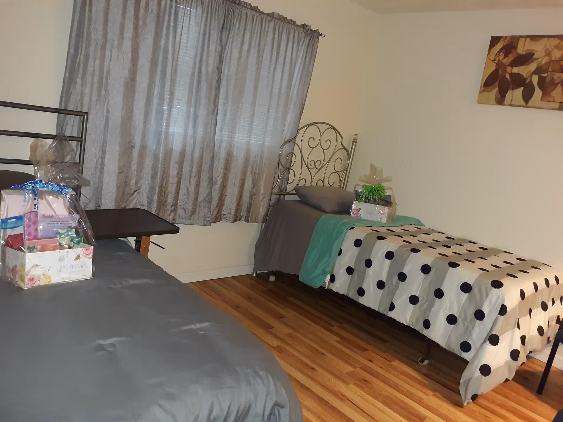 Two single beds with polka dot and gray bedding in a small, well-lit bedroom.