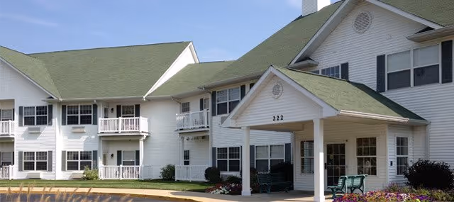 White senior living facility with green pitched roofs and a covered front entrance.
