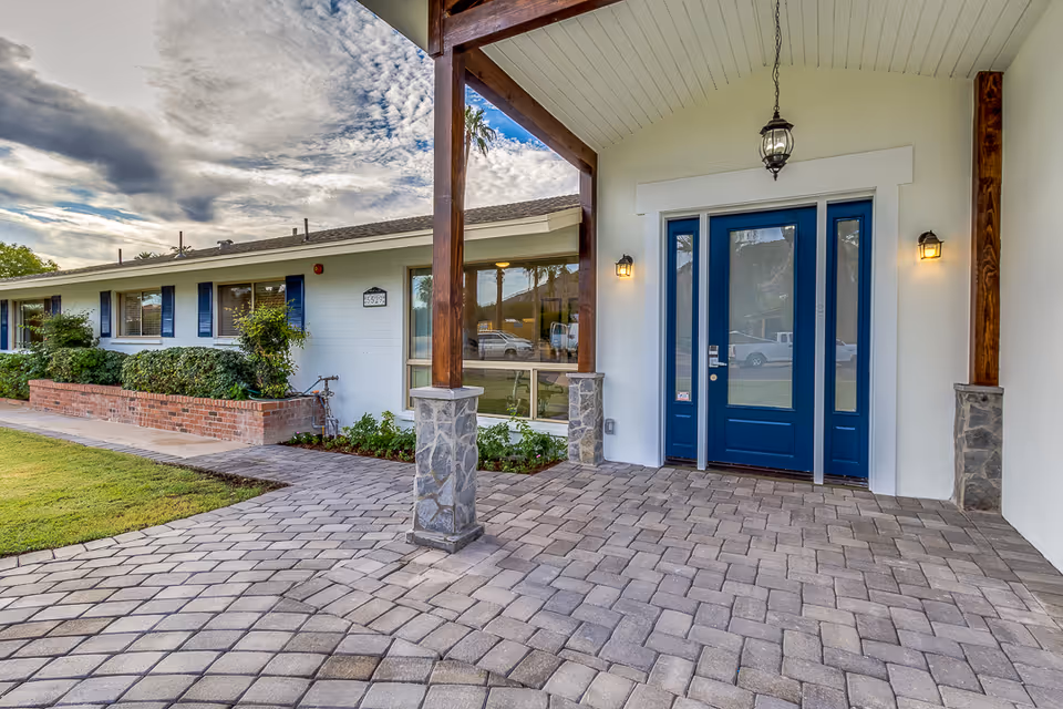 Front entrance of Vista Living Camelback with blue doors, stone columns, and brick planters.