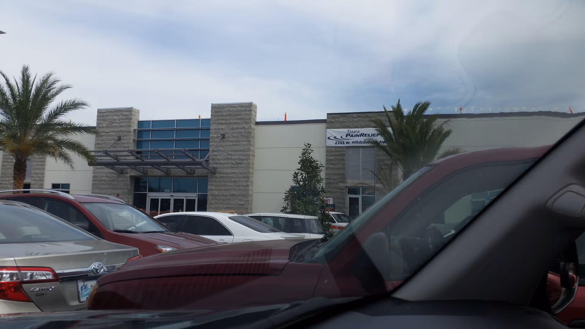 Exterior view of Tampa Pain Relief Centers building with palm trees and parked cars.
