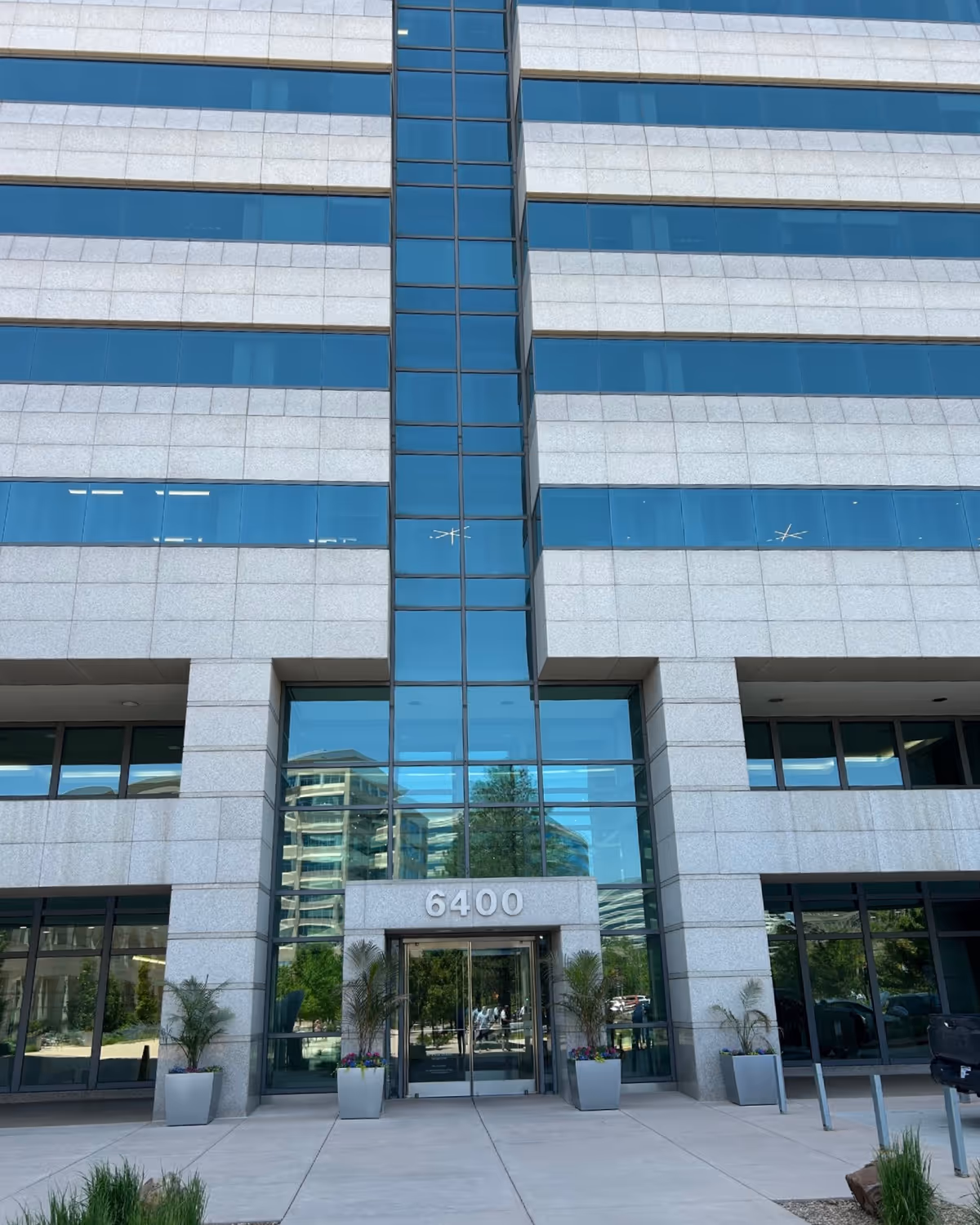Modern glass-fronted building exterior with a central entrance and the address 6400.