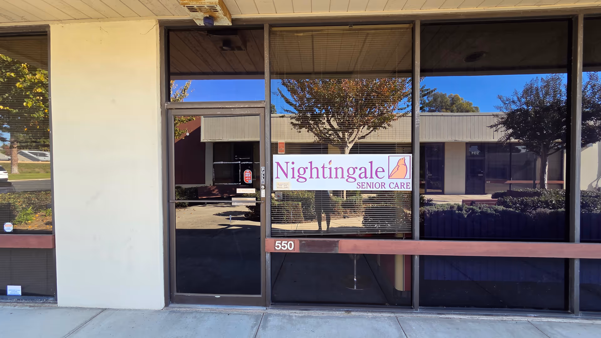 Glass storefront entrance with a Nightingale Senior Care sign and reflection of outdoors.