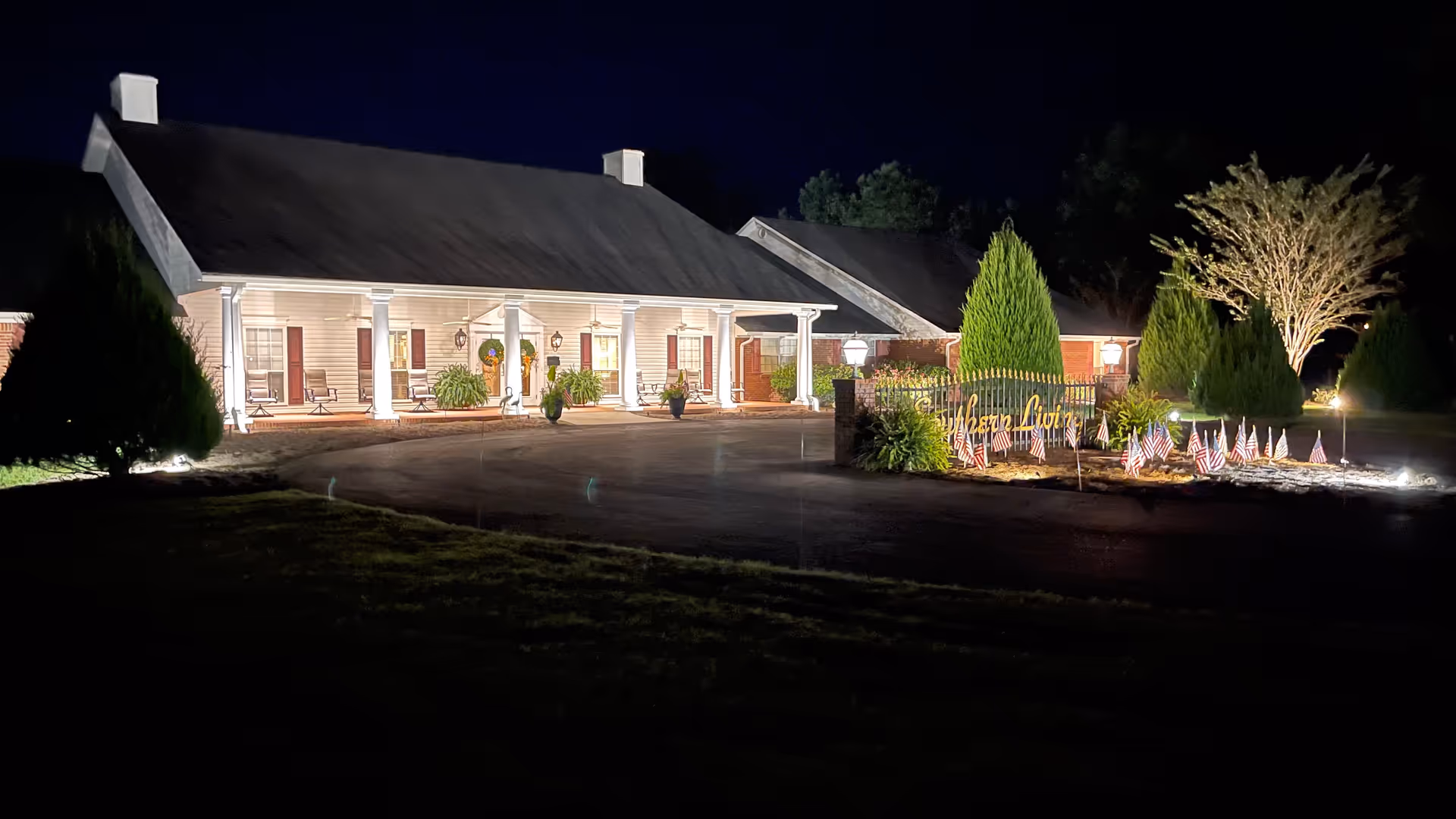 Nighttime exterior of a single-story assisted living facility with a lit entrance and sign.