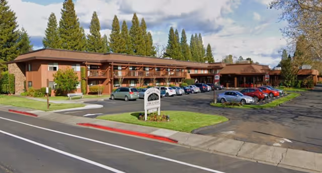 Exterior view of Silverado Orchards Retirement Community with parked cars and a two-story building.
