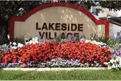 Lakeside Village sign with red flowers and greenery in front.