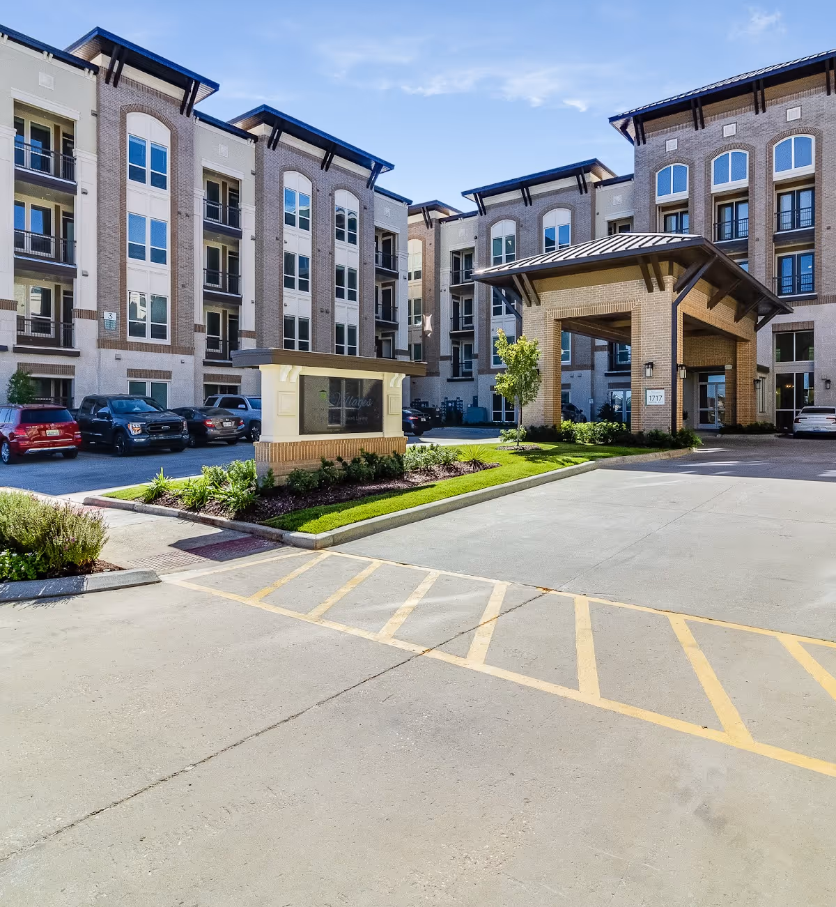 Exterior view of a multi-story senior living building with a covered entrance and parking.
