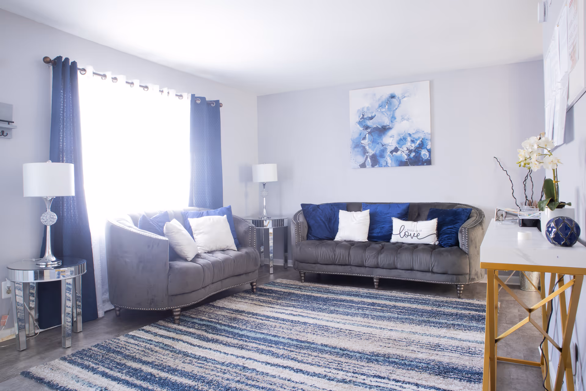 Bright lounge with two gray sofas, blue accents, and modern decor in a cozy living room.