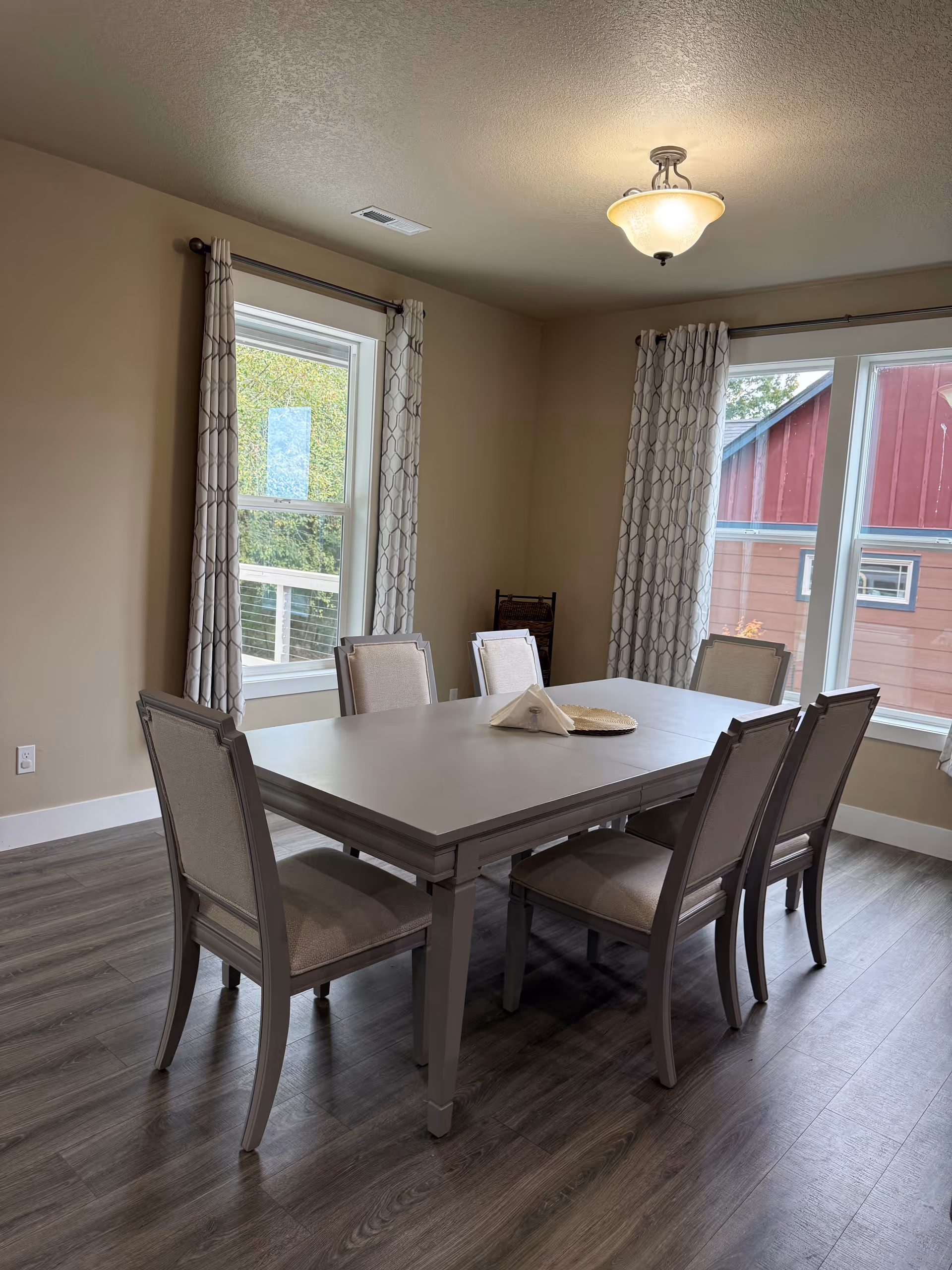 A bright dining room with a large table and eight upholstered chairs by windows