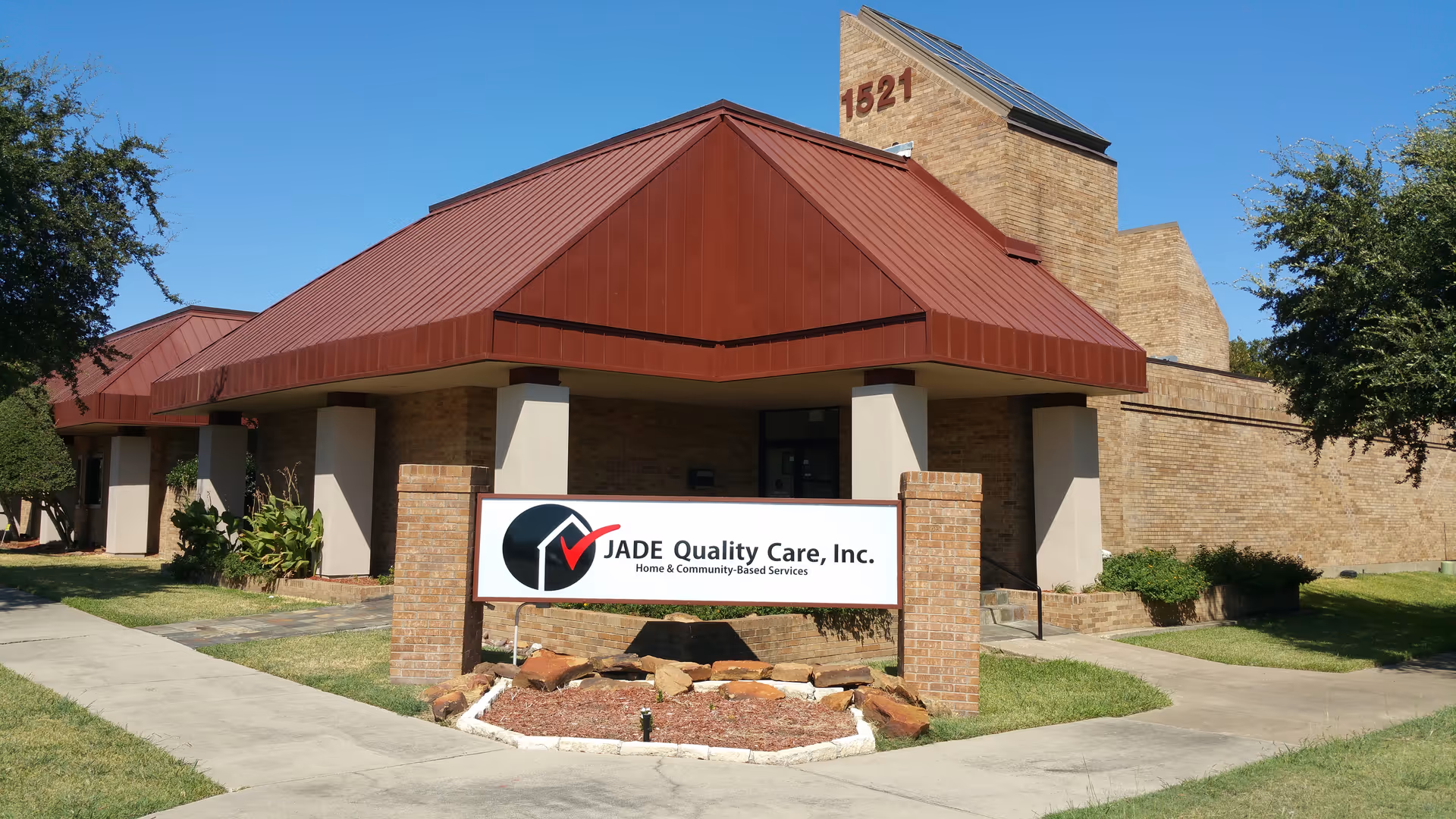 Exterior view of Jade Quality Care Inc facility with red-roofed entrance and sign.