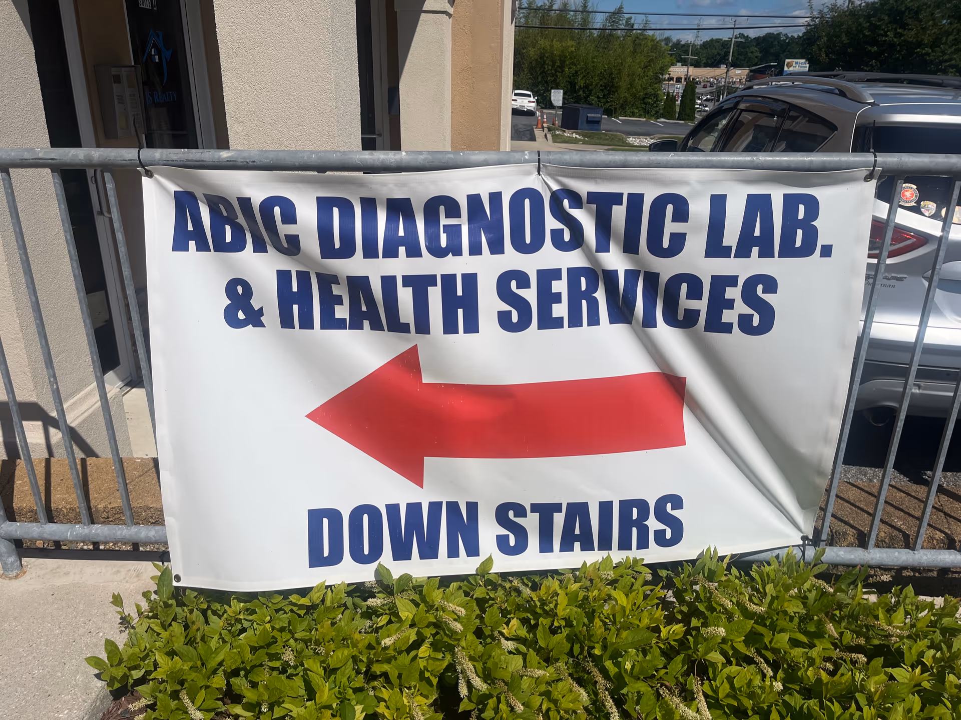 Exterior banner on railing directs to ABIC Diagnostic Lab and Health Services downstairs.