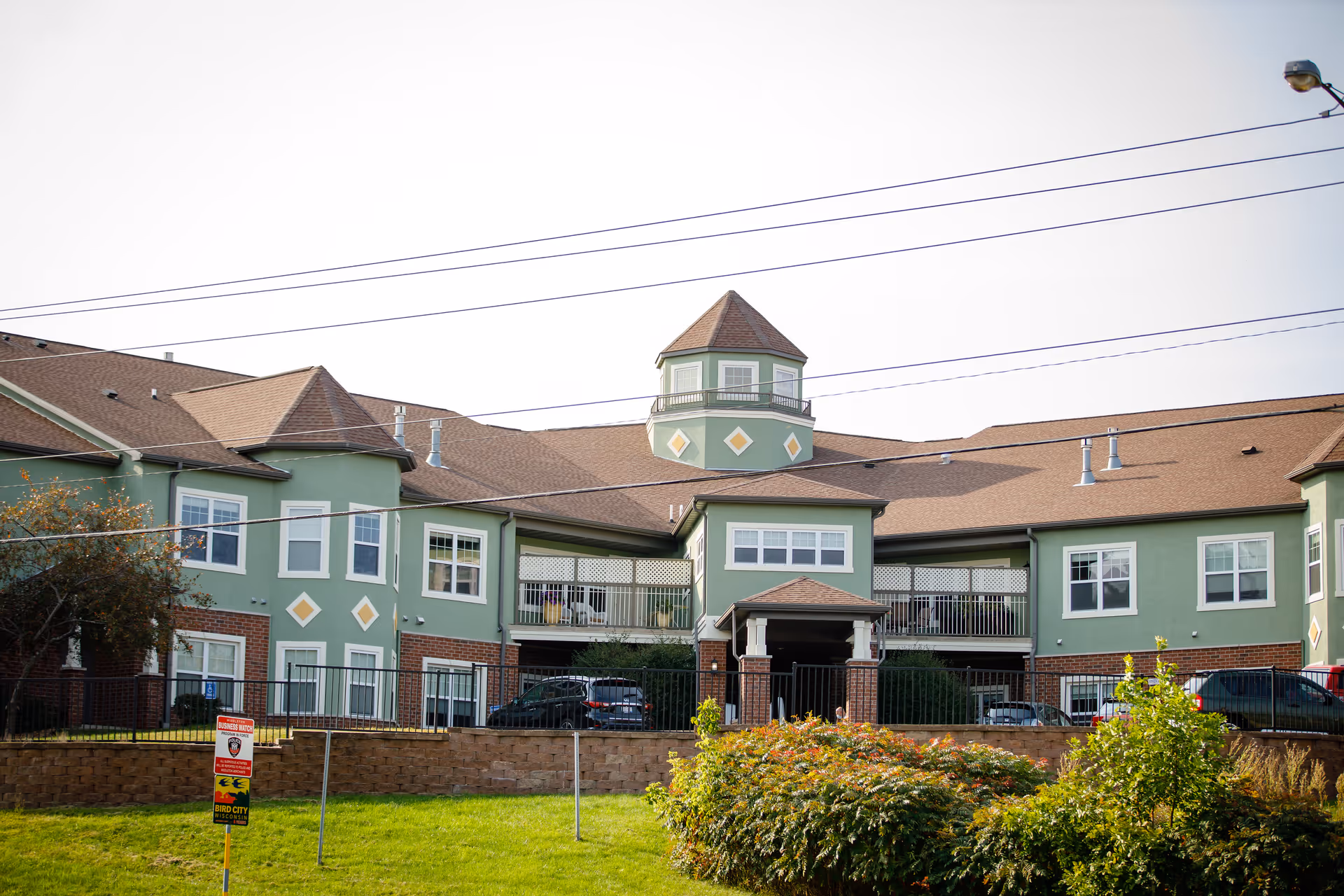 Exterior view of Sage Meadow of Middleton, a green senior living building with a central tower.