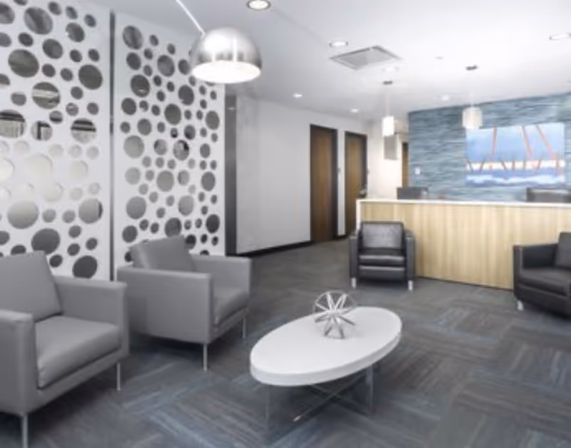 Modern lobby with gray chairs, circular wall decor, and a reception desk.