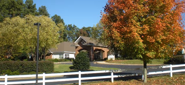 Carriage House Senior Living Community exterior with autumn trees and a white fence.