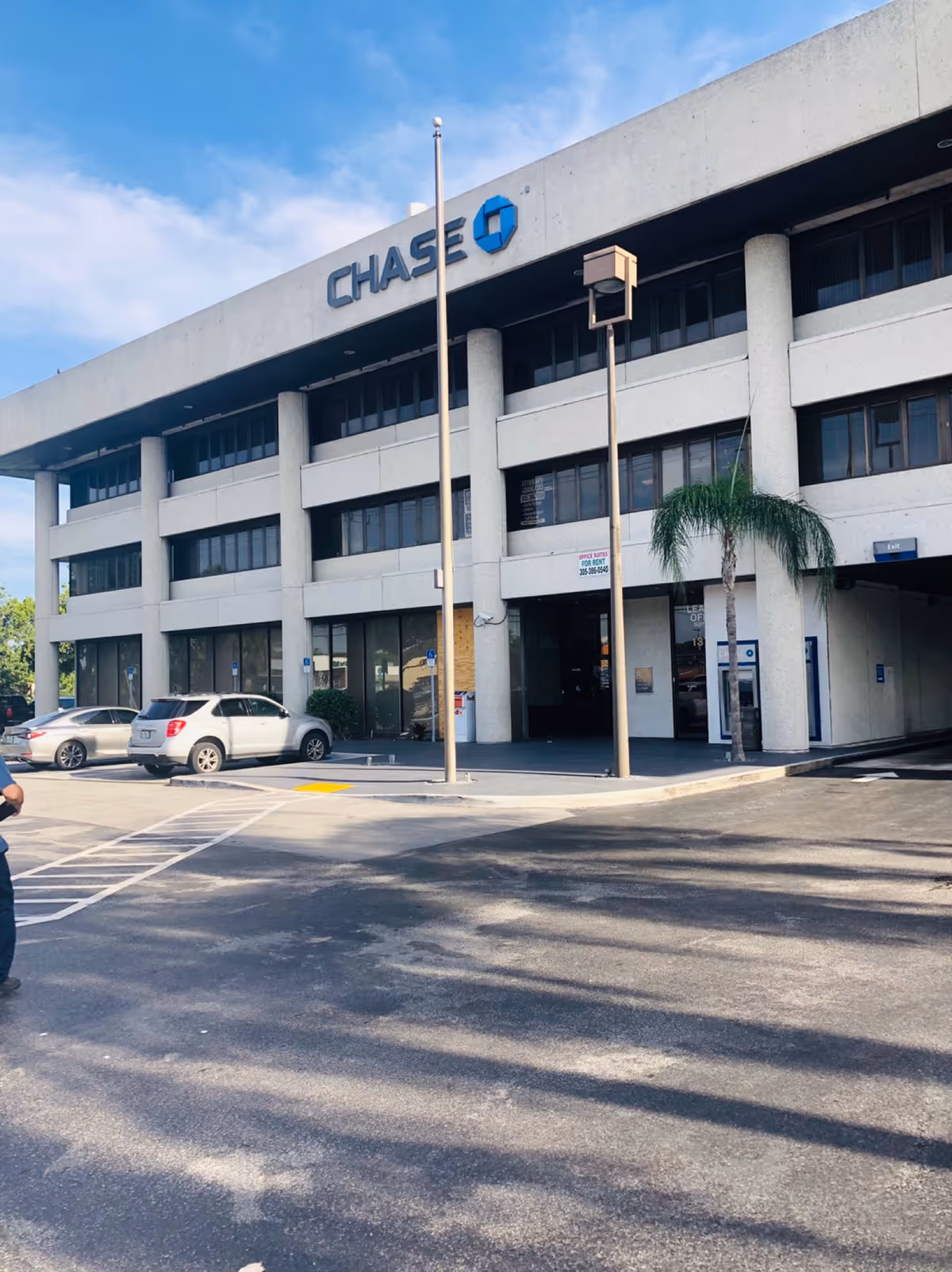 Exterior view of a Chase bank building with parked cars and a palm tree