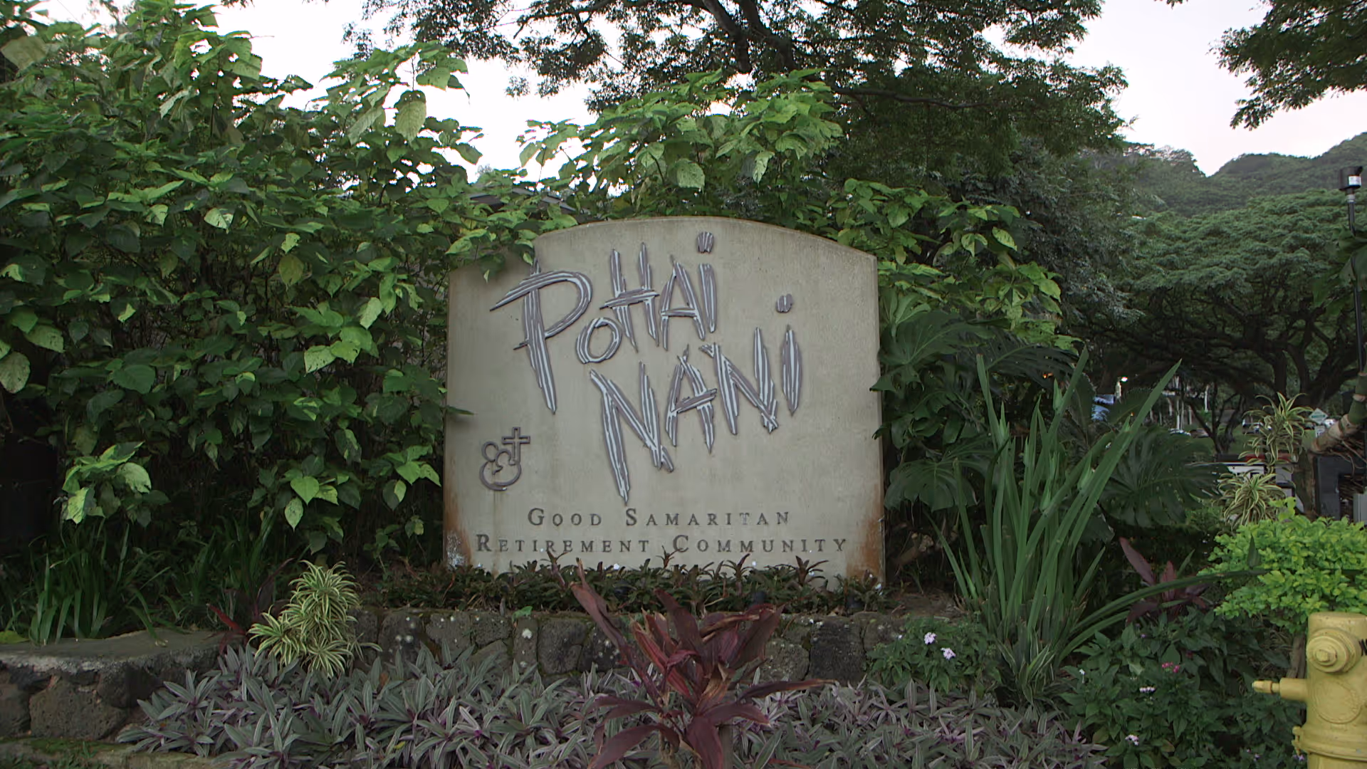 Exterior sign for Pohai Nani Good Samaritan Retirement Community with lush greenery around.
