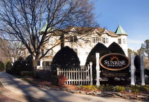 Exterior view of Sunrise Senior Living with sign and landscaped entrance.
