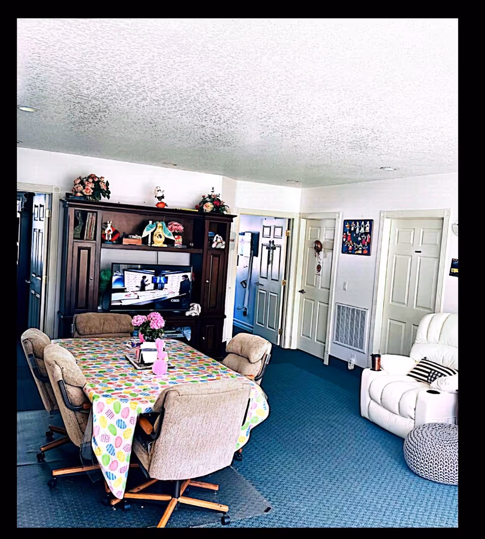 Common living/dining area with a long table, upholstered chairs, a TV cabinet, and sofa.
