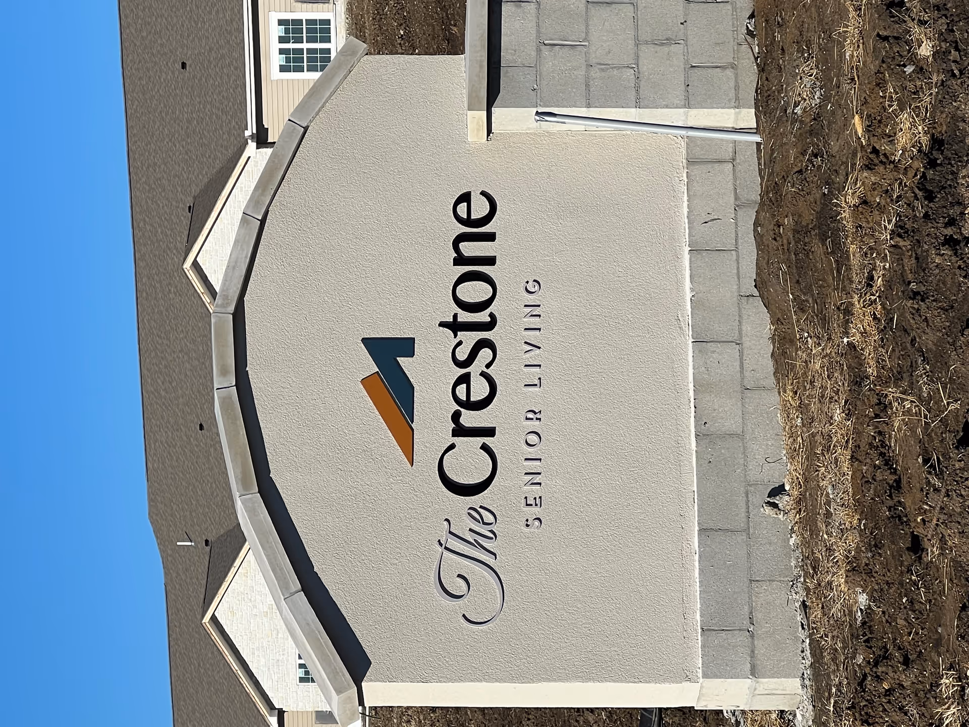 Exterior view of The Crestone Senior Living sign on a beige wall.