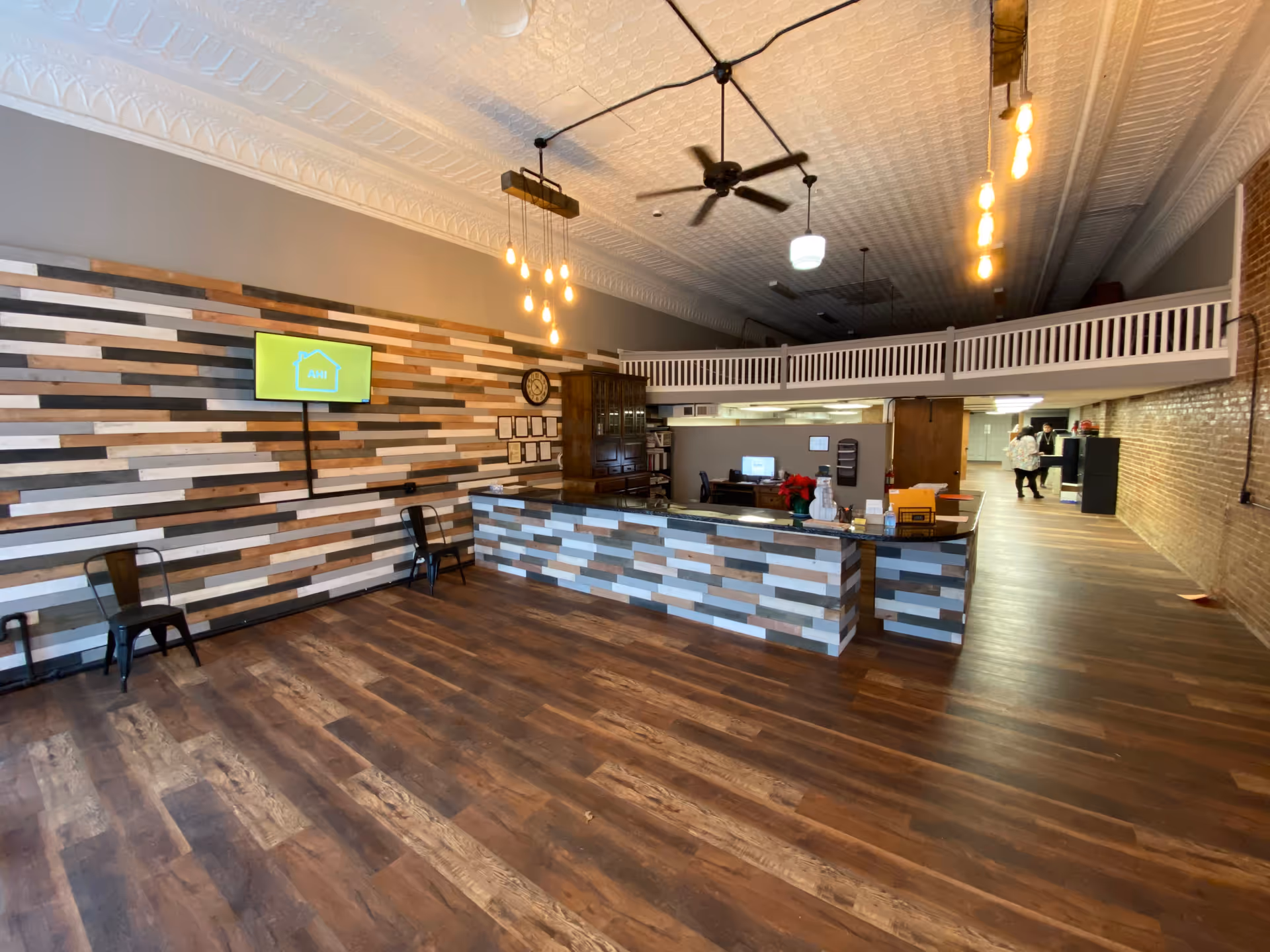 Reception area with wood-paneled wall, front desk, and mezzanine in a senior living facility.