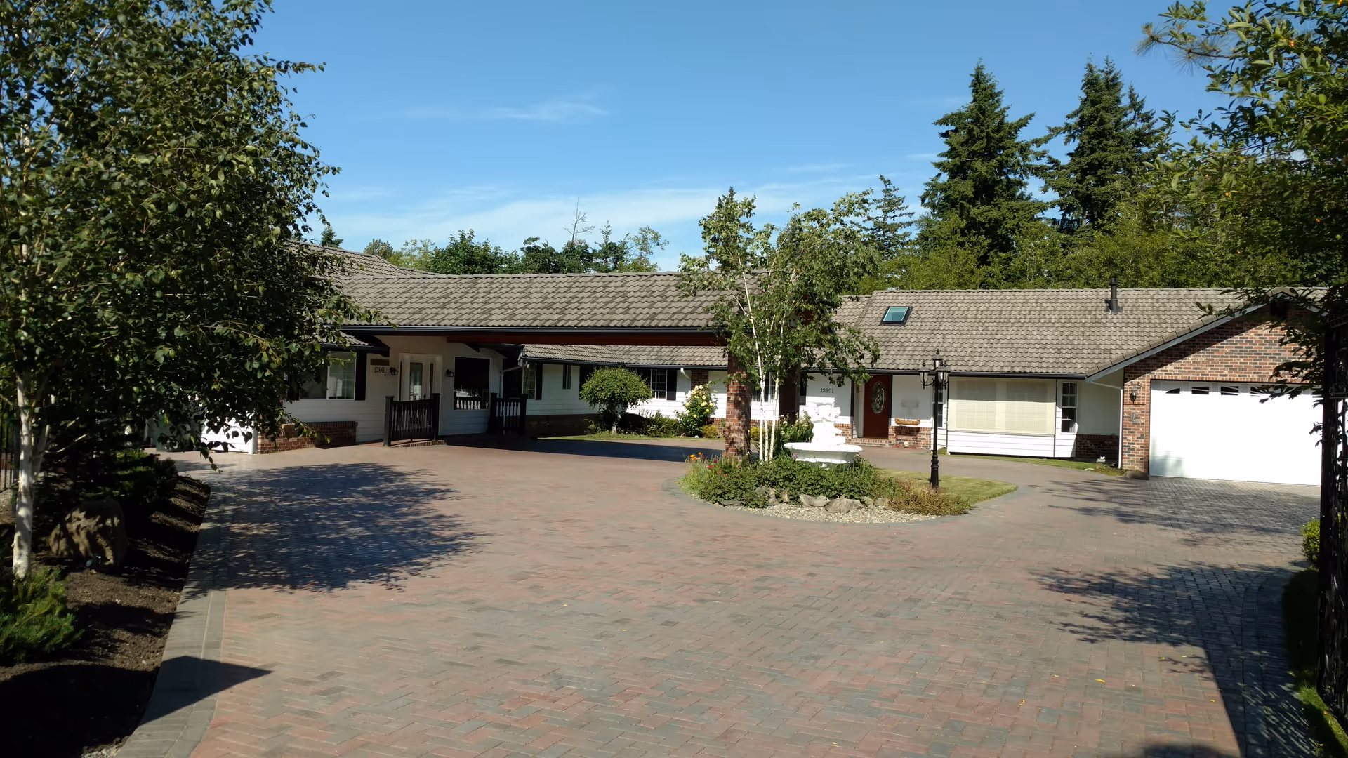 Front view of a single-story senior living home with driveway and trees.