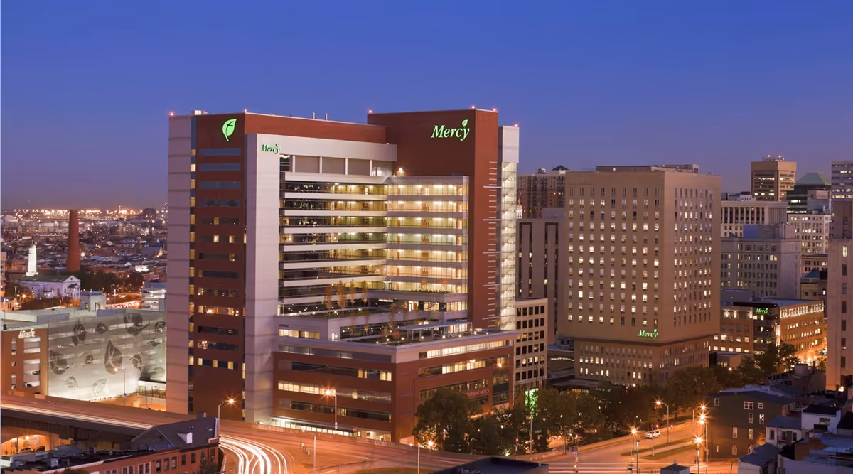 Nighttime exterior view of the Mercy center building with illuminated windows.