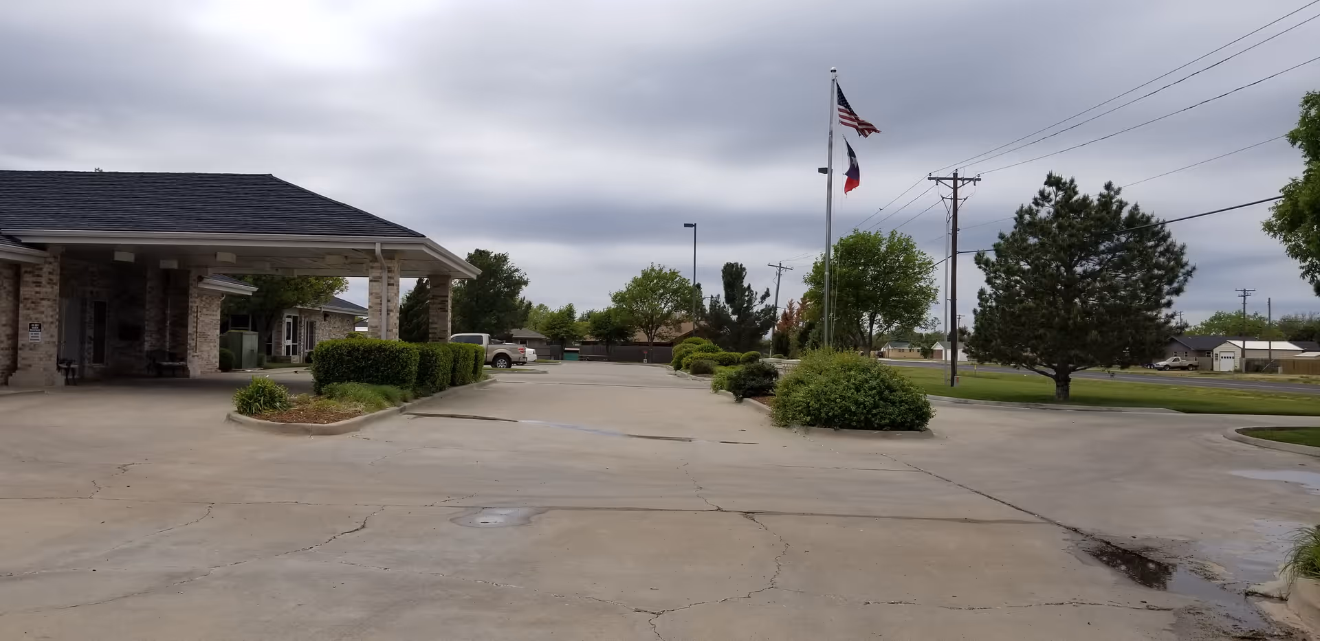 Exterior view of The Seasons Assisted Living with driveway, flagpoles, and landscaped grounds.