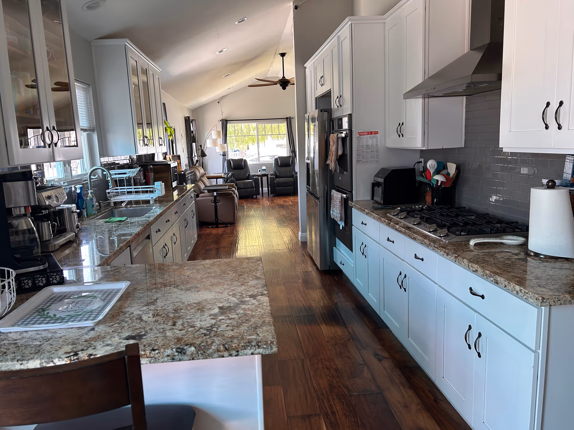 Bright kitchen with white cabinets, granite countertops, island, and open living area.