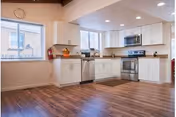 Bright kitchen with white cabinets, stainless steel appliances, and wood flooring.