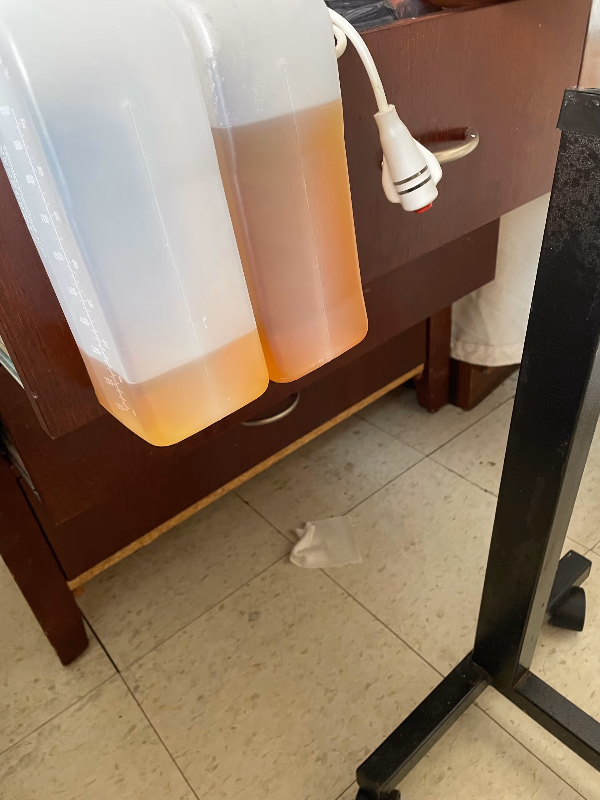 Two large beverage syrup containers hang under a cabinet in a kitchen prep area.