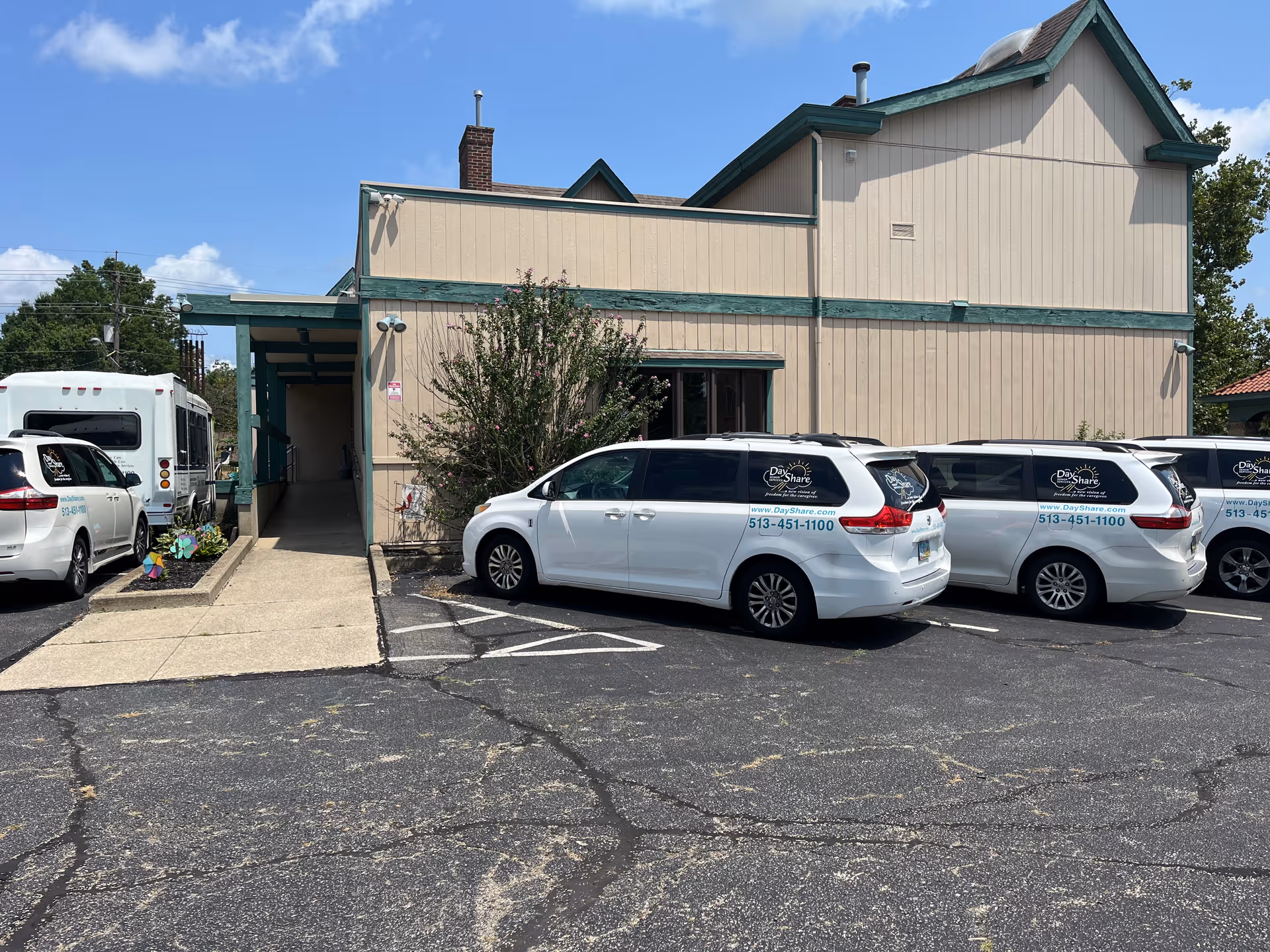 Exterior view of Day Share Senior Services building with parked white vans in front.