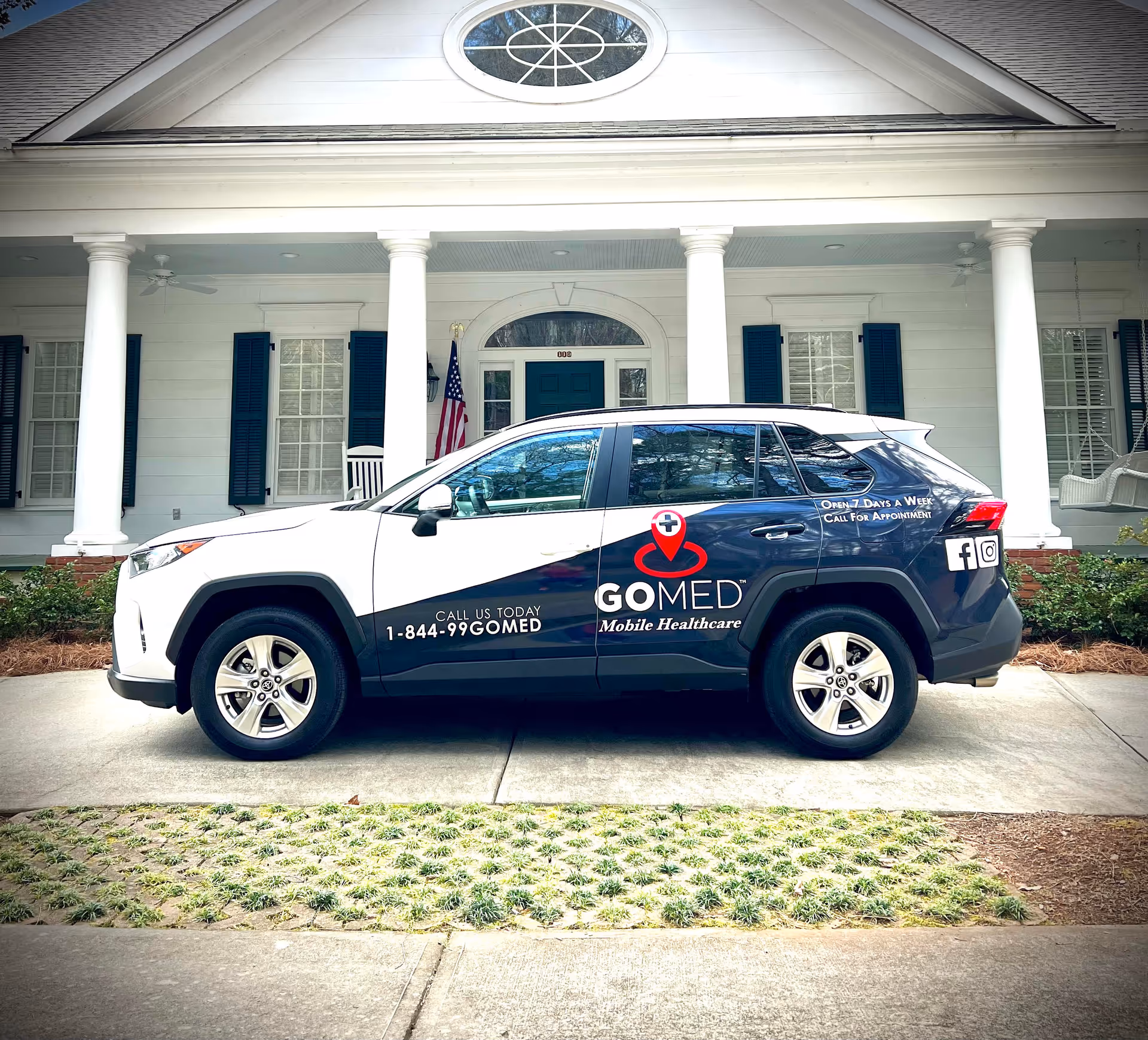A branded GOMED mobile healthcare SUV parked in front of a white colonial-style building.