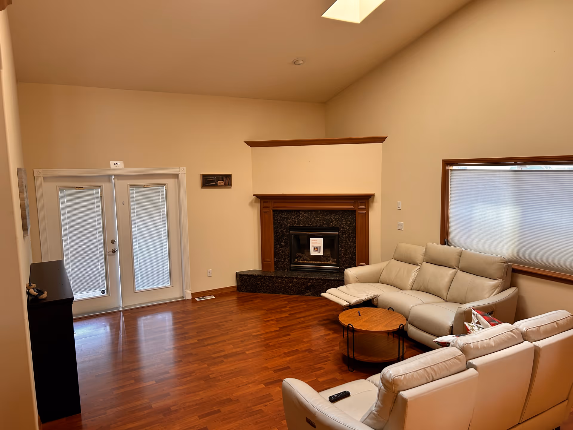 Bright living room with beige walls, a fireplace, hardwood floor, and white sectional seating.