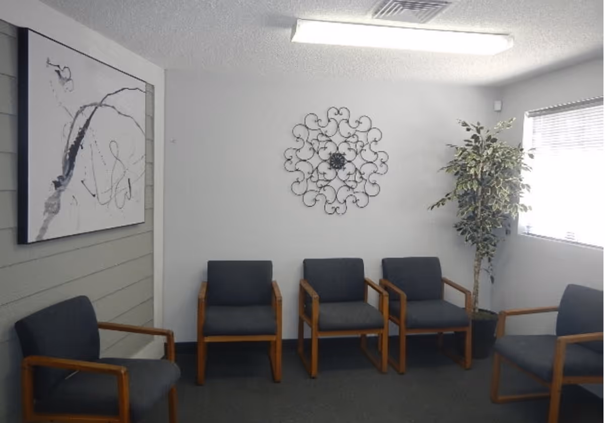 Empty waiting area in a senior care facility with blue chairs and wall decor.