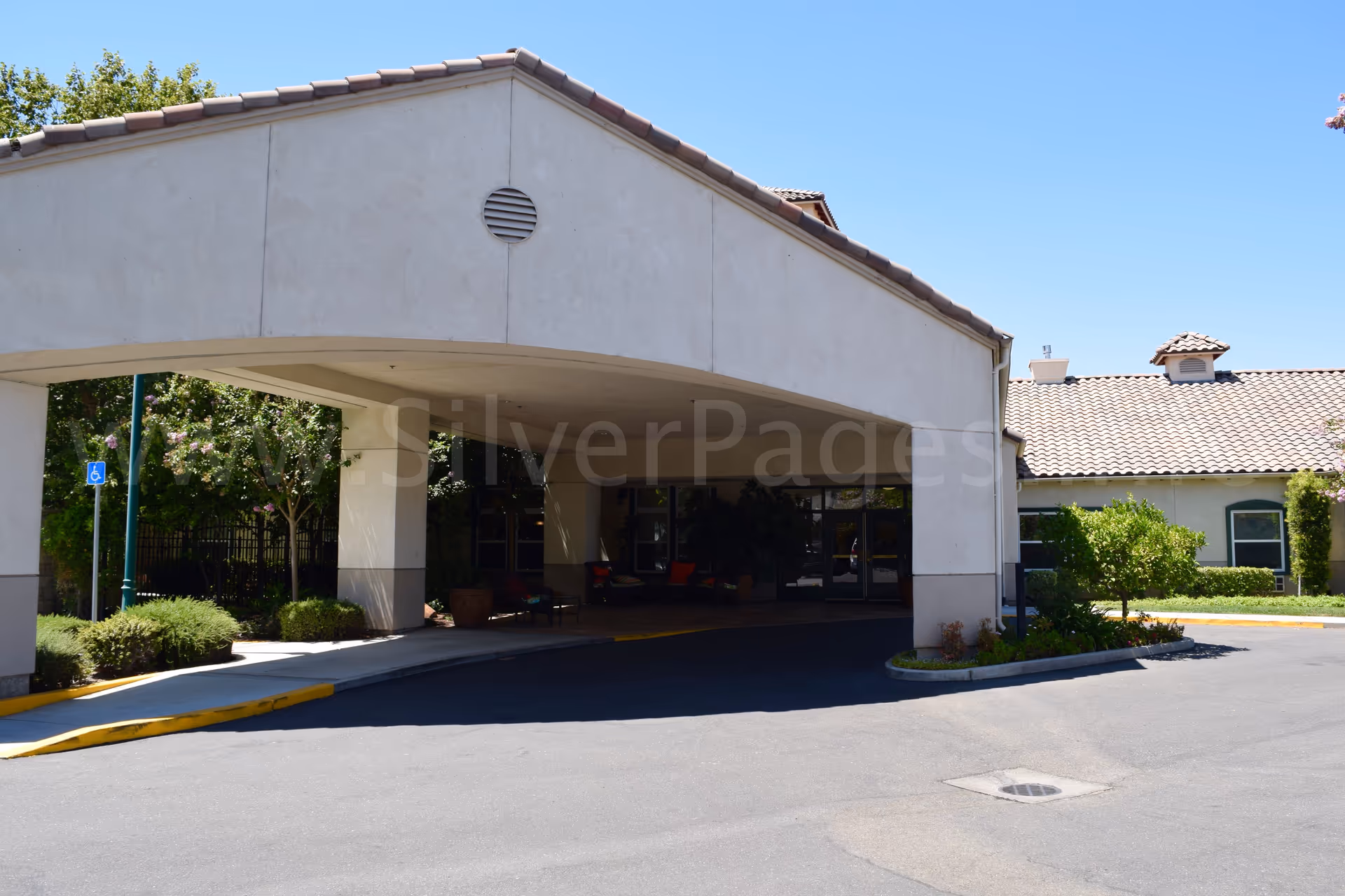 Entrance to a senior living facility with a covered driveway and landscaping.