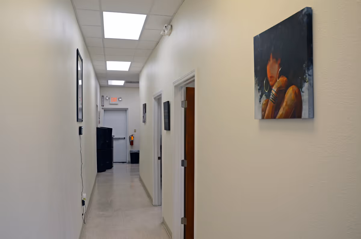 Neutral interior hallway in a senior living facility with wall art and an exit at end.