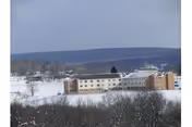 Exterior view of Meadow View Nursing Center on a snowy hillside with leafless trees.