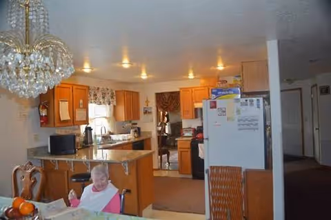 Open kitchen and dining area of a senior facility with a resident seated.