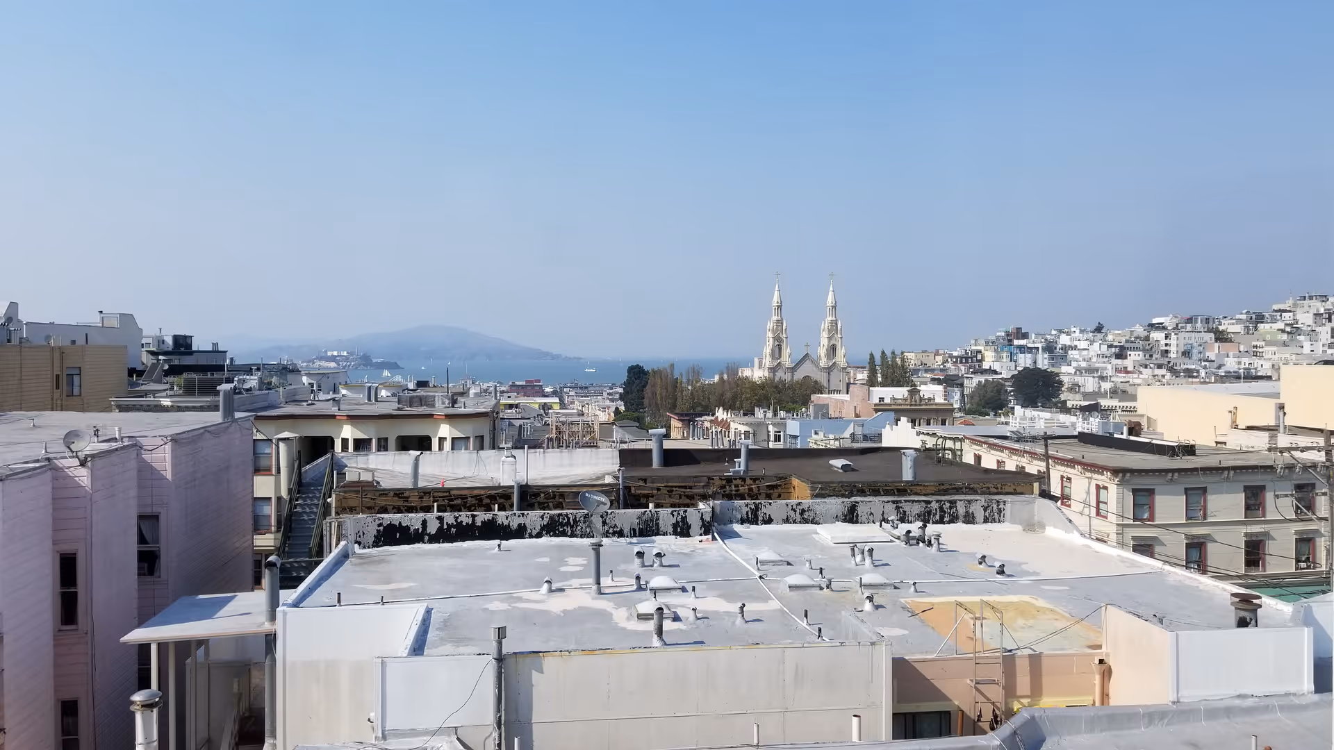 A panoramic city skyline seen from rooftops with distant church towers.