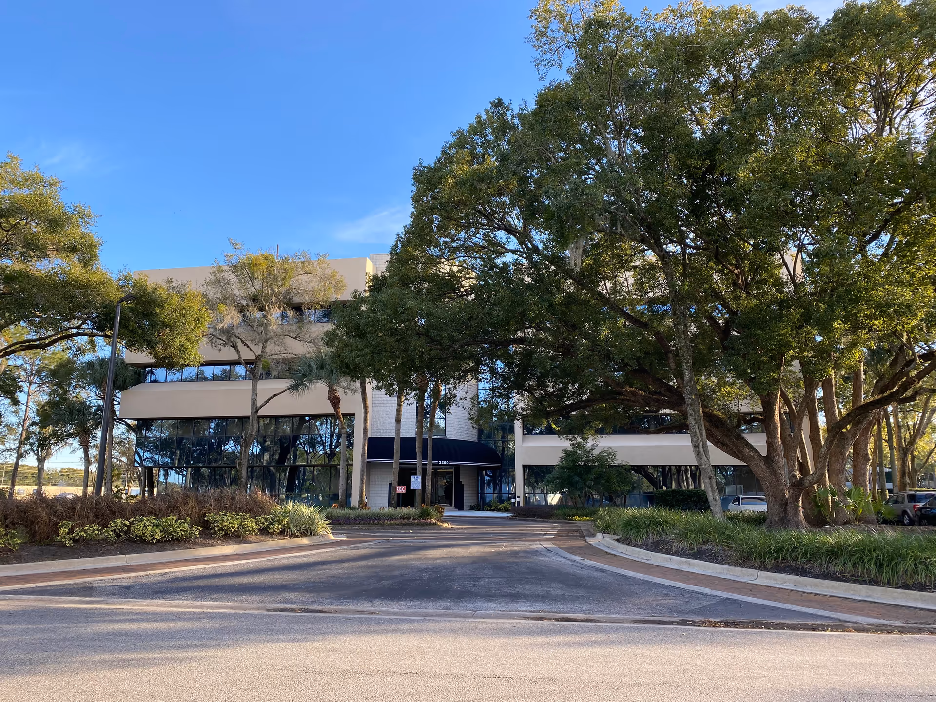 Exterior view of a modern senior living facility with a curved driveway and tall trees