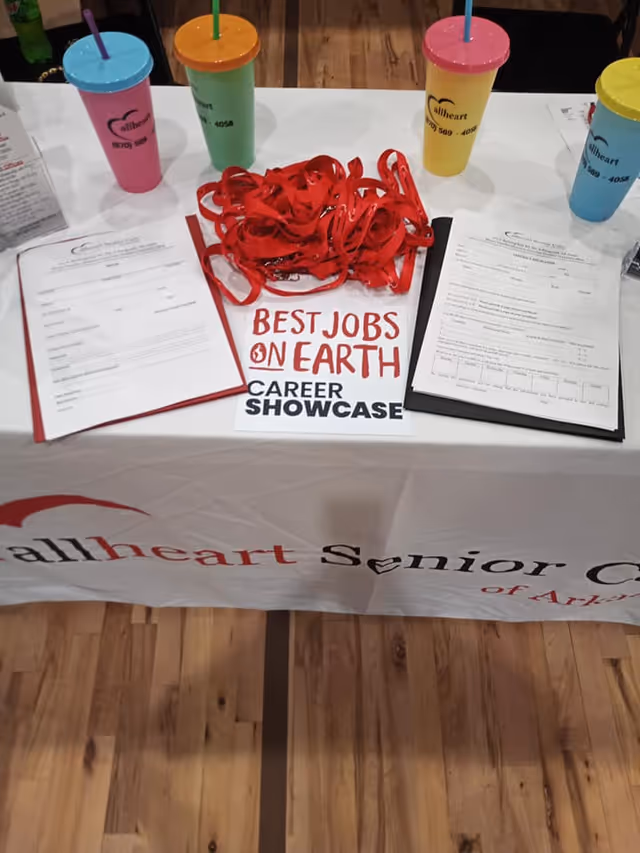 Table setup with colorful cups, red lanyards, and promotional materials for Allheart Senior Care.