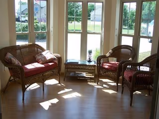 Sunlit wicker seating area with four chairs and a coffee table by large windows