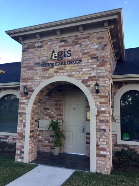 Brick building with arch entry and Aegis Senior Care Group sign at the front.