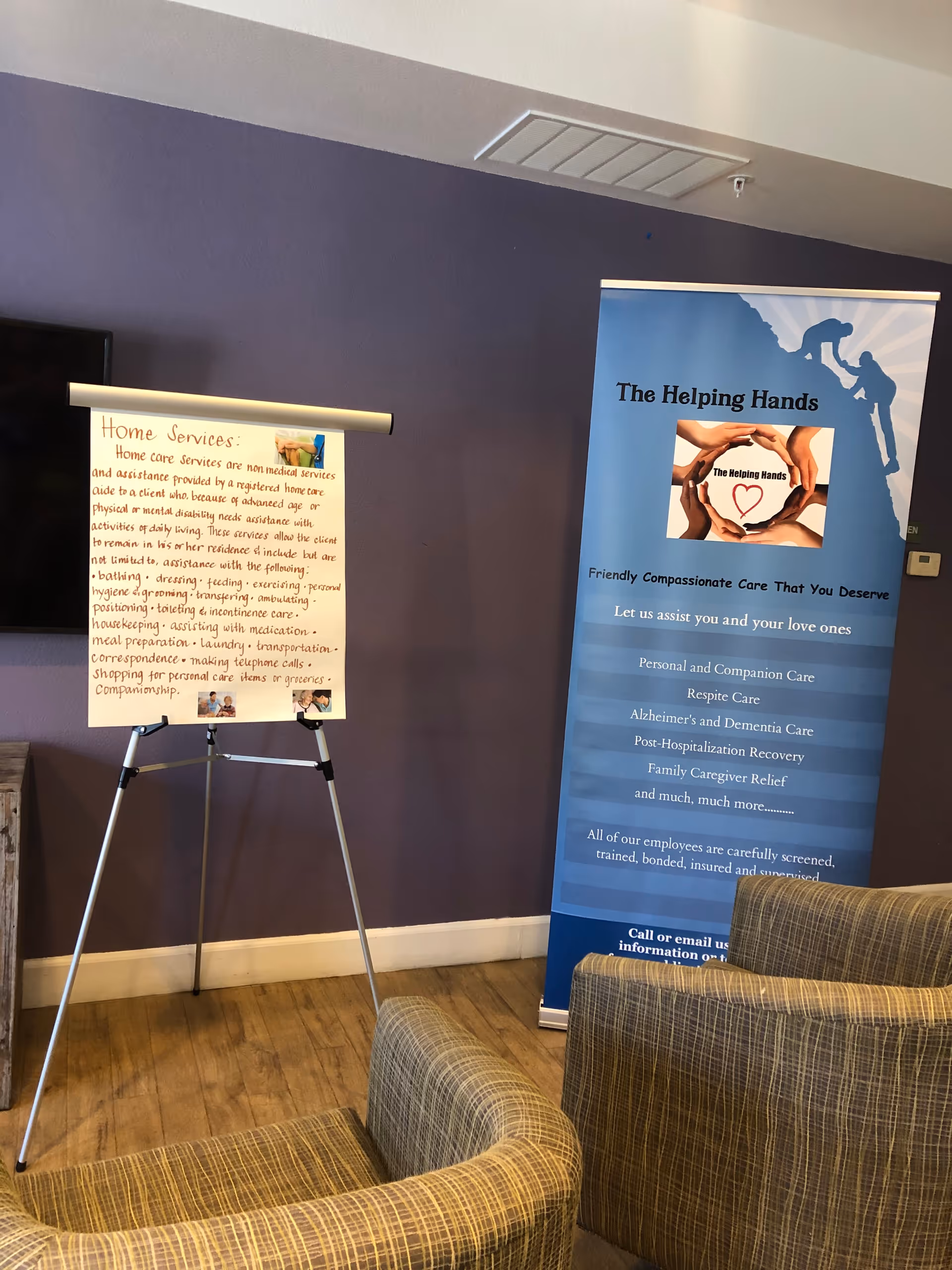 Indoor lobby area with a blue The Helping Hands banner and an information display.