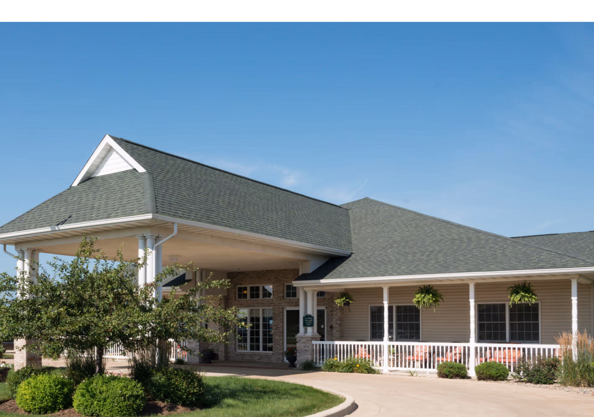 Front view of a single-story senior living facility with a covered entrance and landscaping.