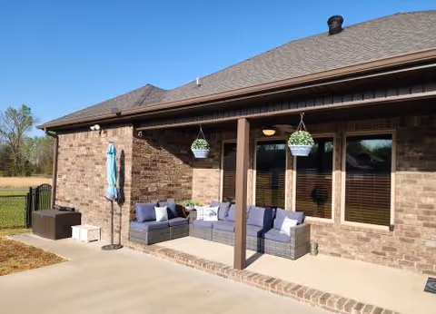Exterior of Austin Senior Living with a covered patio, outdoor seating, and hanging planters.