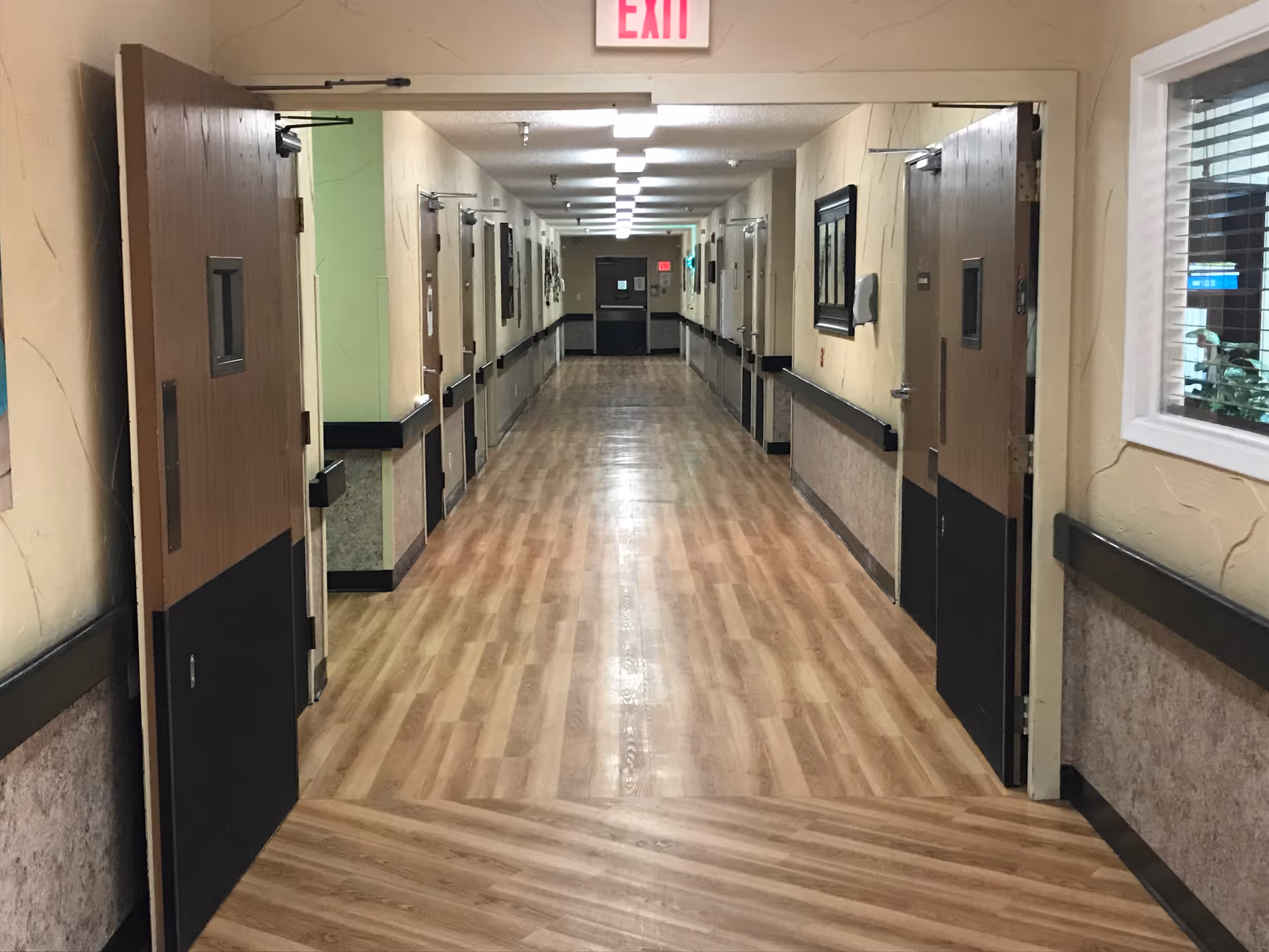 A long corridor with doors on both sides in a senior living facility.