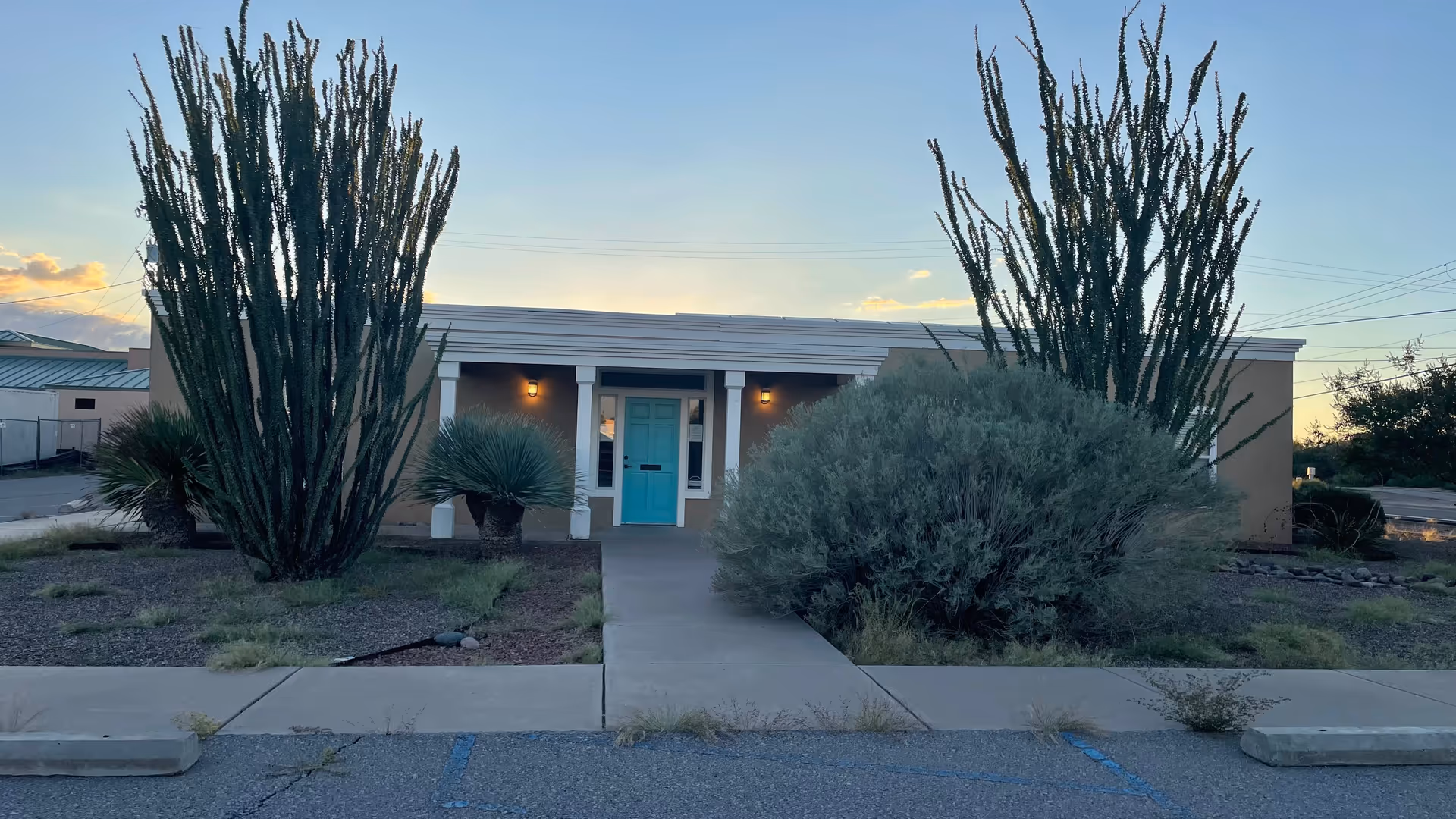 Front view of Mountain Shadows Home Care Inc. facility with turquoise door and desert landscaping.