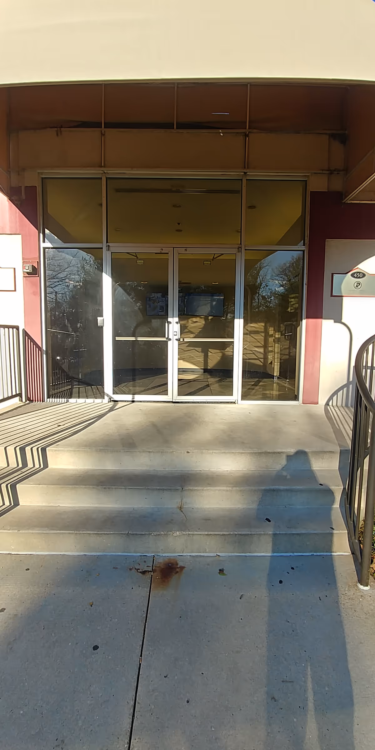Front entrance of a senior living facility with glass doors and concrete steps.