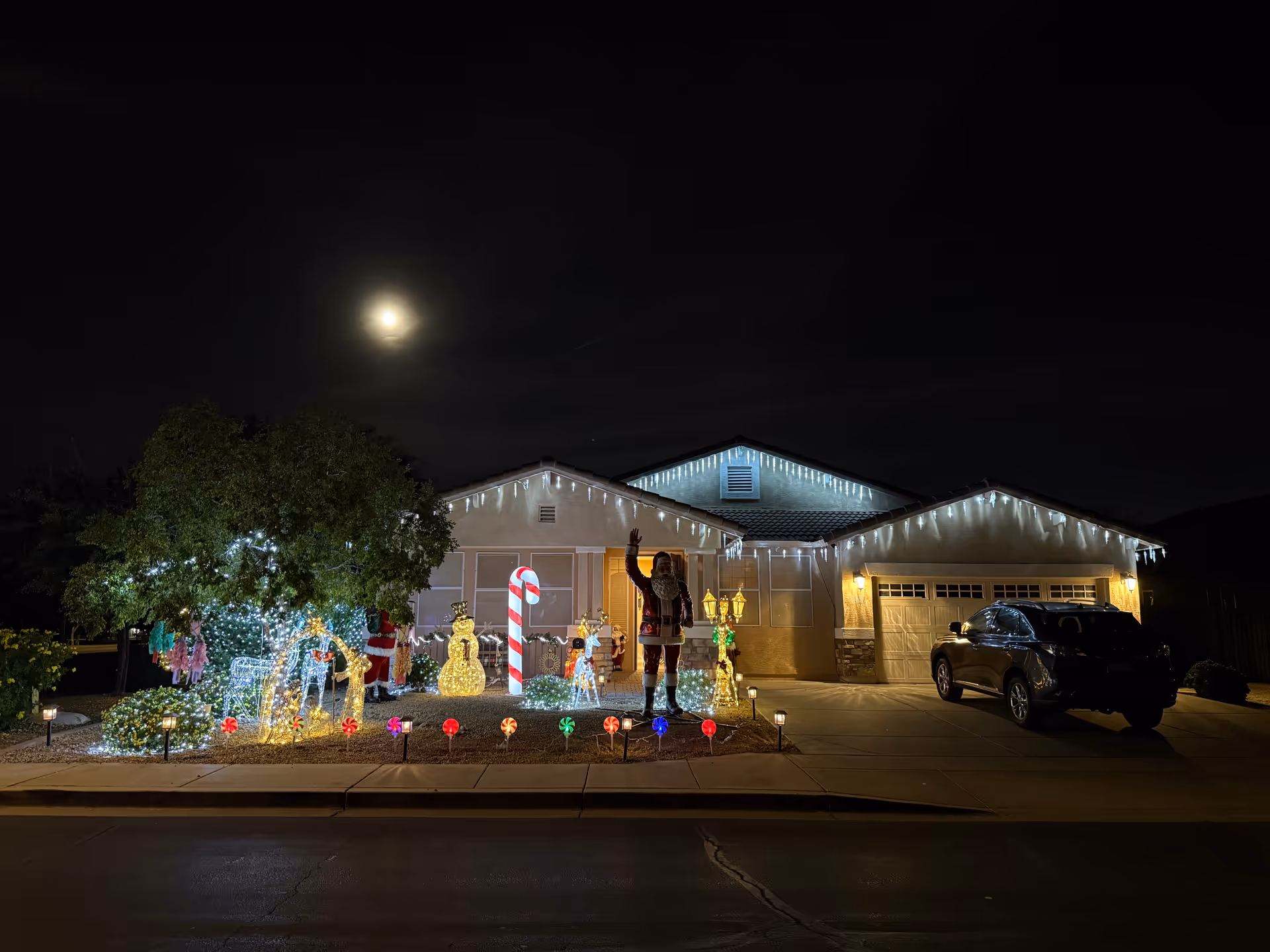 Night view of a front-facing assisted living facility illuminated by festive lights and a person.
